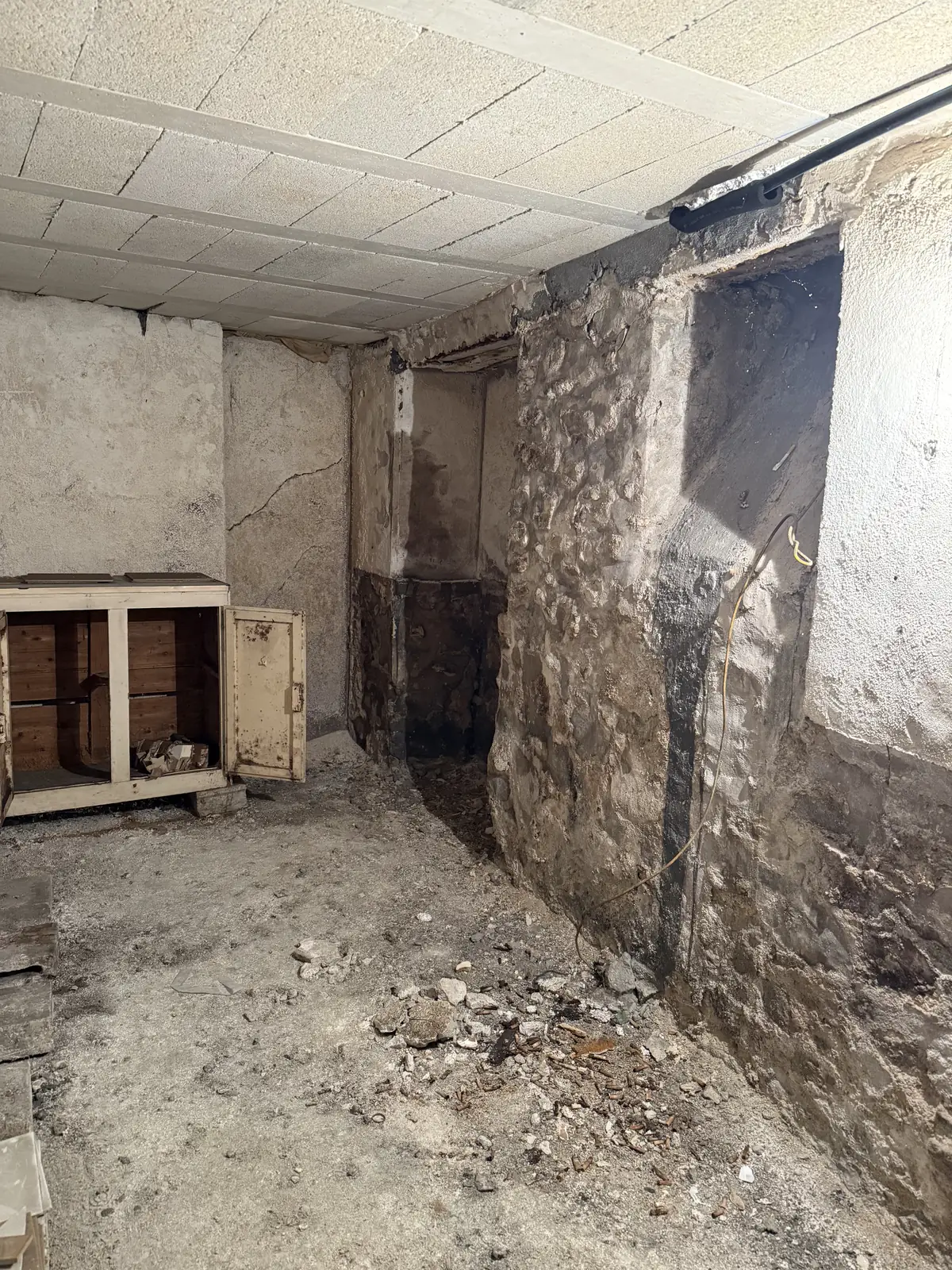 Avant : le pied de mur en pierre marqué par l’humidité, et le sol en terre battue.
